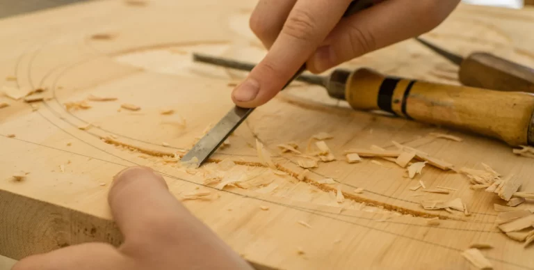 Artisan sculptant une planche de bois au ciseau