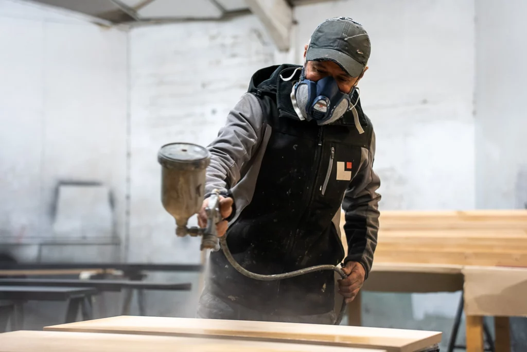 Ouvrier en combinaison pulvérisant de la peinture - Photographie industrielle