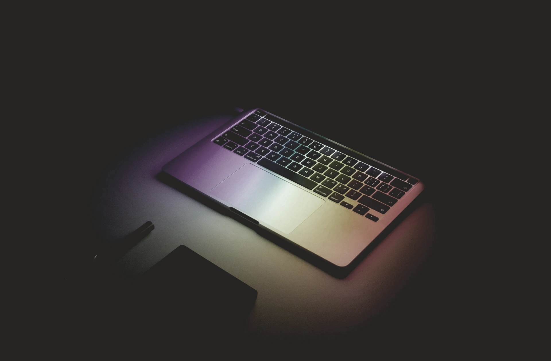 Ordinateur portable ouvert éclairé d’une lumière colorée dans la pénombre